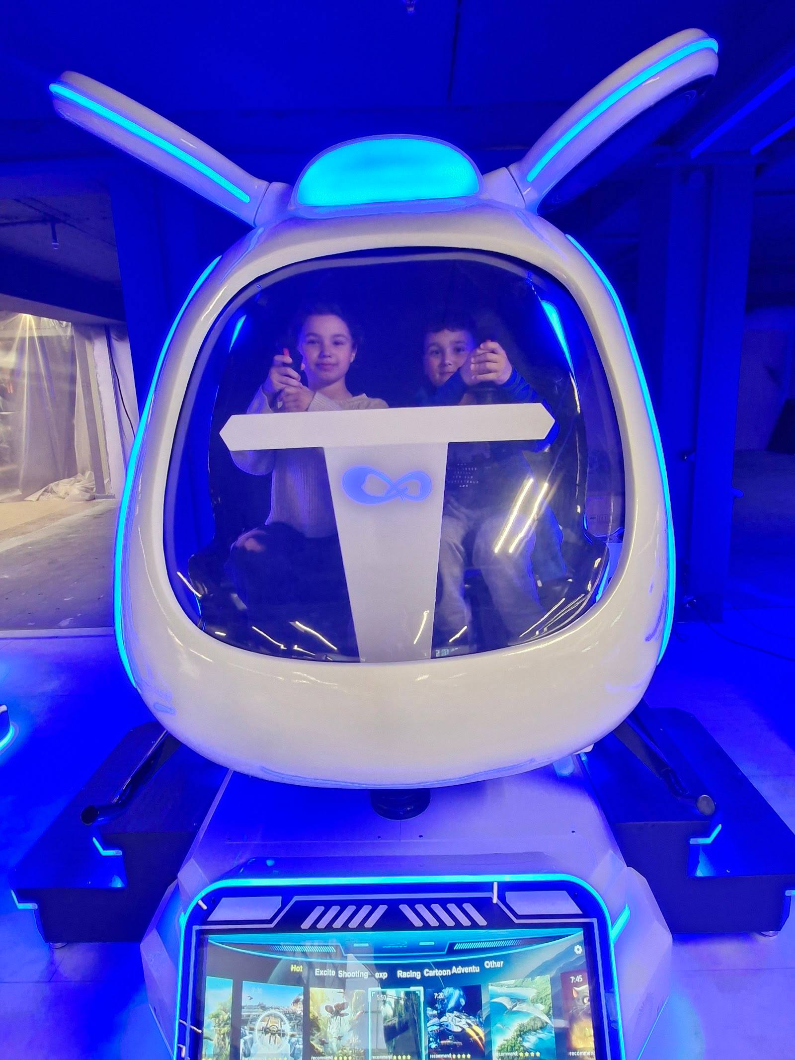 Interactive futuristic ride with glowing cockpit and animated robot arms