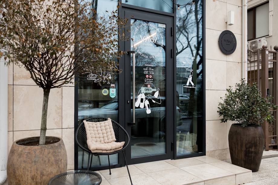 Modern storefront with black glass doors, minimalist seating, and contemporary facade design