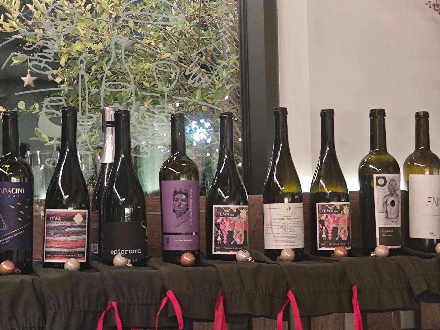Wine bottles displayed on draped table with decorative foliage backdrop