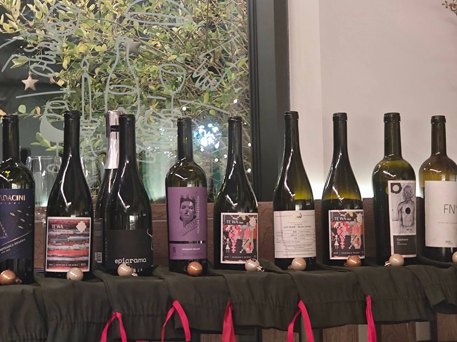 Wine bottles displayed on draped table with decorative foliage backdrop