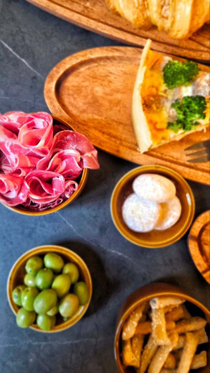 Charcuterie spread with cured meats, olives, cheese, and bread on slate surface