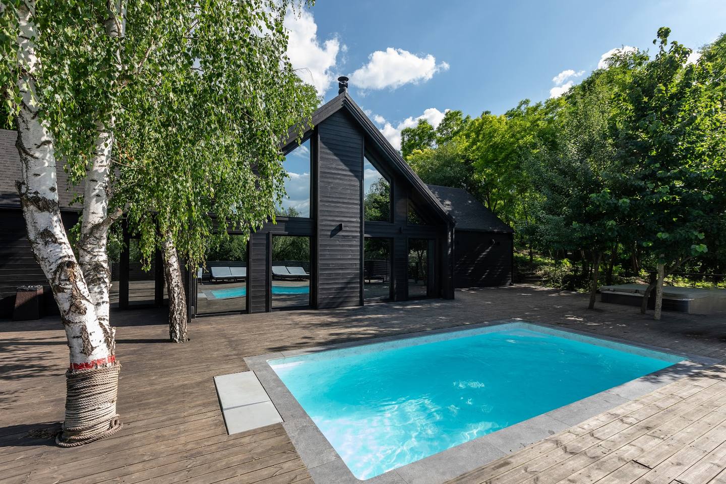 Modern black cottage with heated pool and landscaped grounds in natural setting