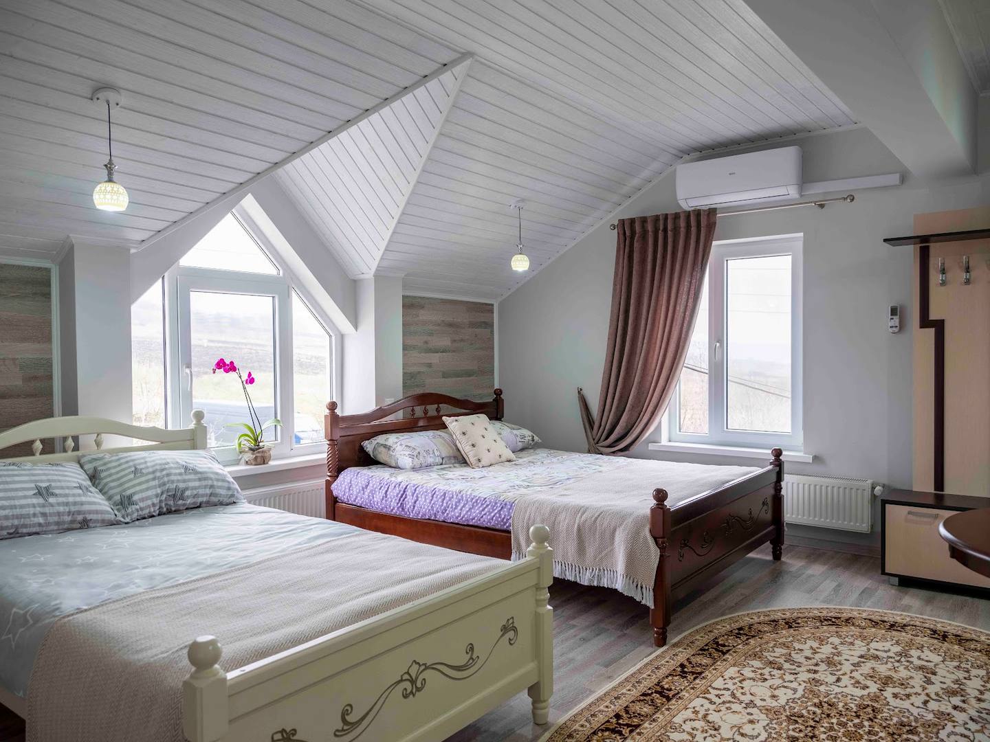 Bright attic bedroom with sloped ceilings, multiple beds, and natural light from dormer windows