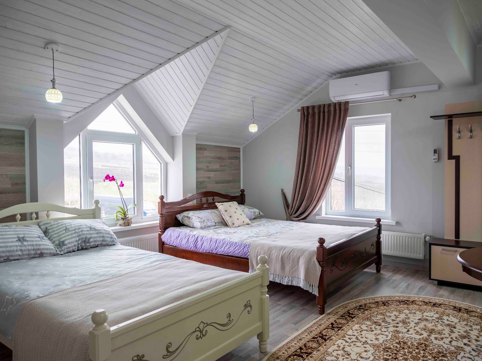 Bright attic bedroom with sloped ceilings, multiple beds, and natural light from dormer windows
