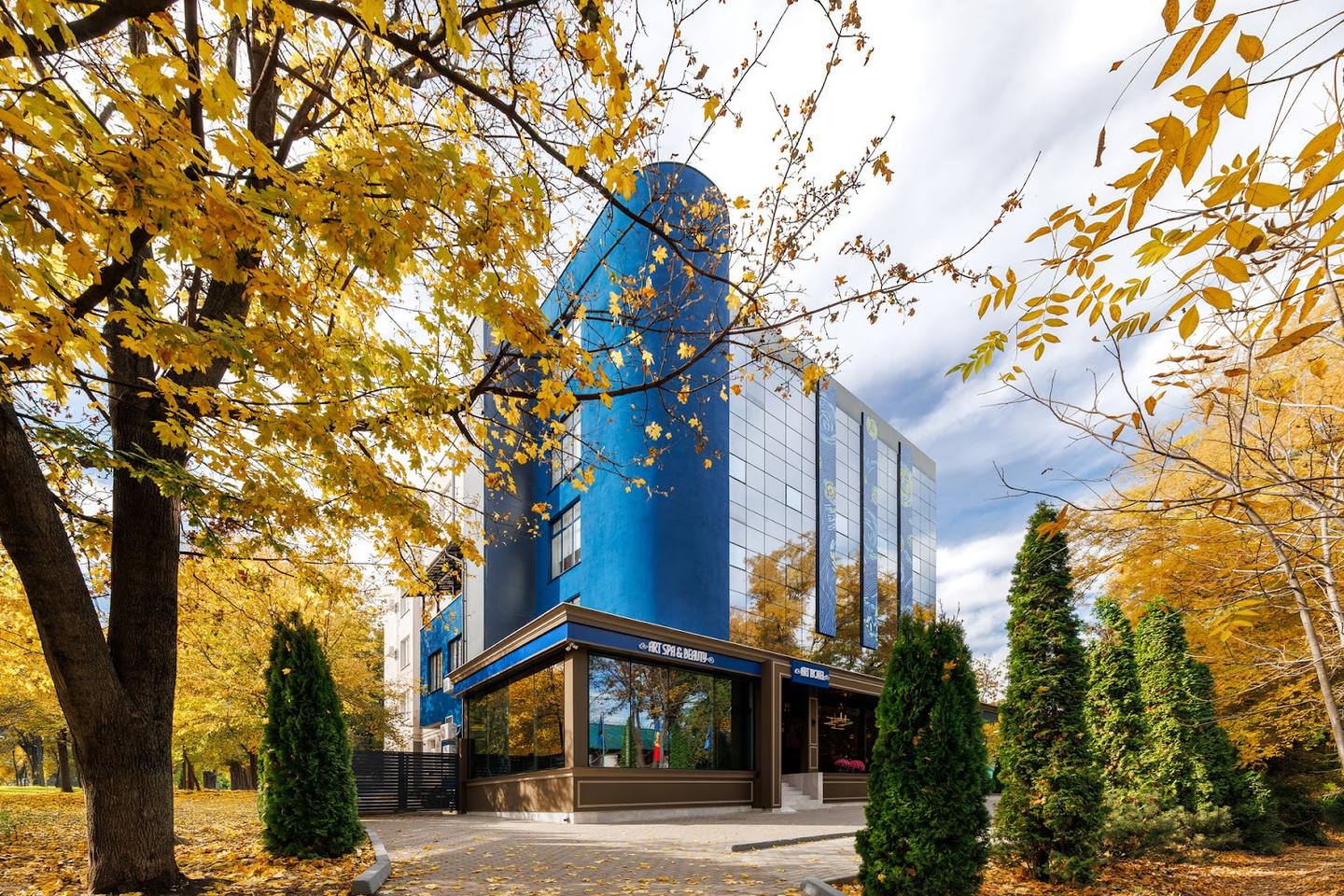 Modern venue with distinctive blue facade and glass entrance, autumn setting