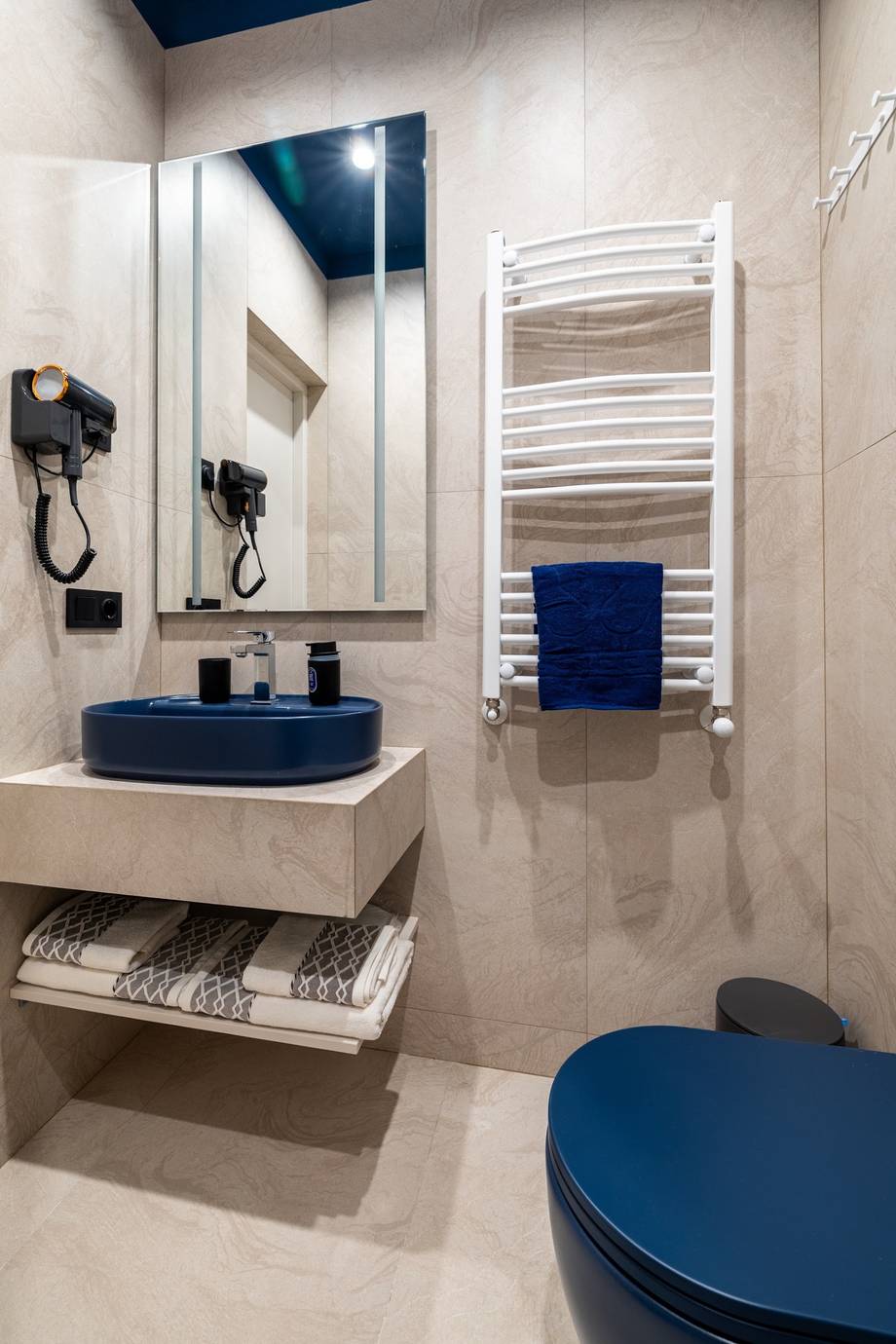 Modern bathroom interior with blue accents, heated towel rack, and contemporary fixtures