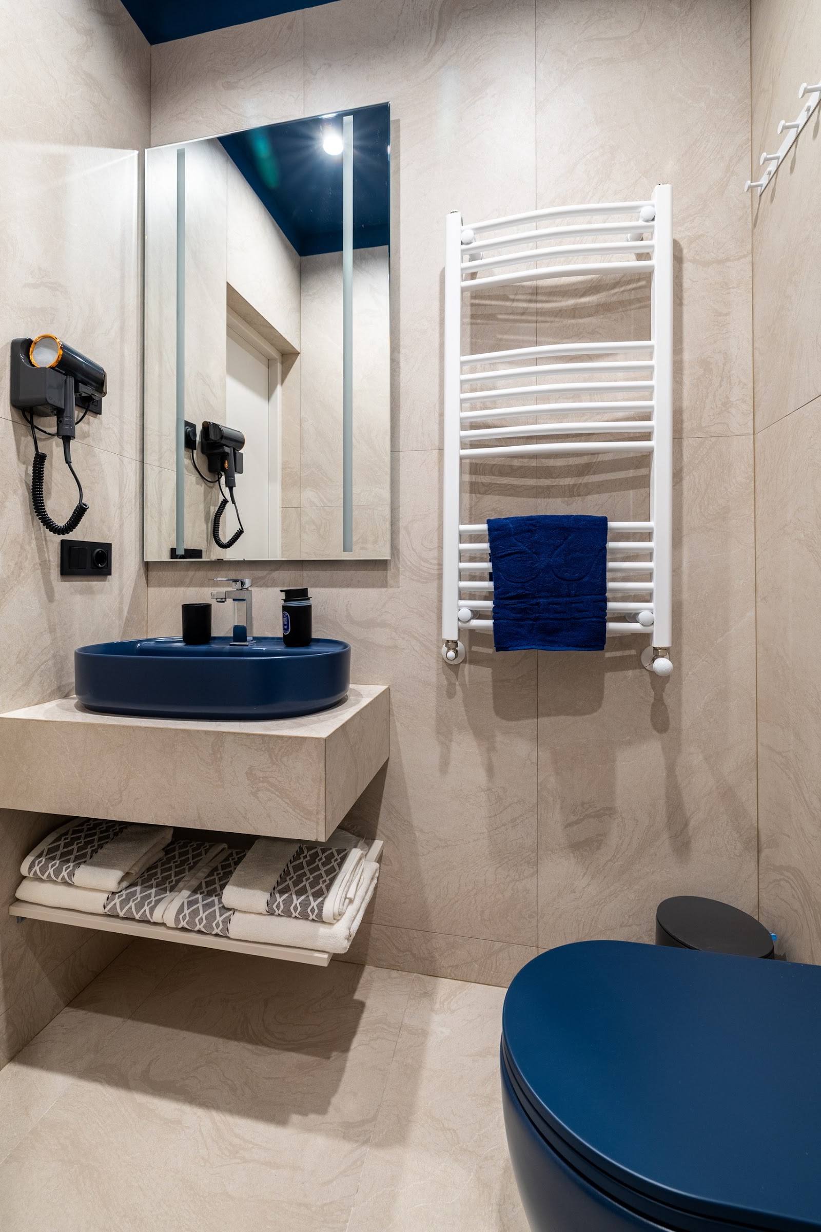 Modern bathroom interior with blue accents, heated towel rack, and contemporary fixtures