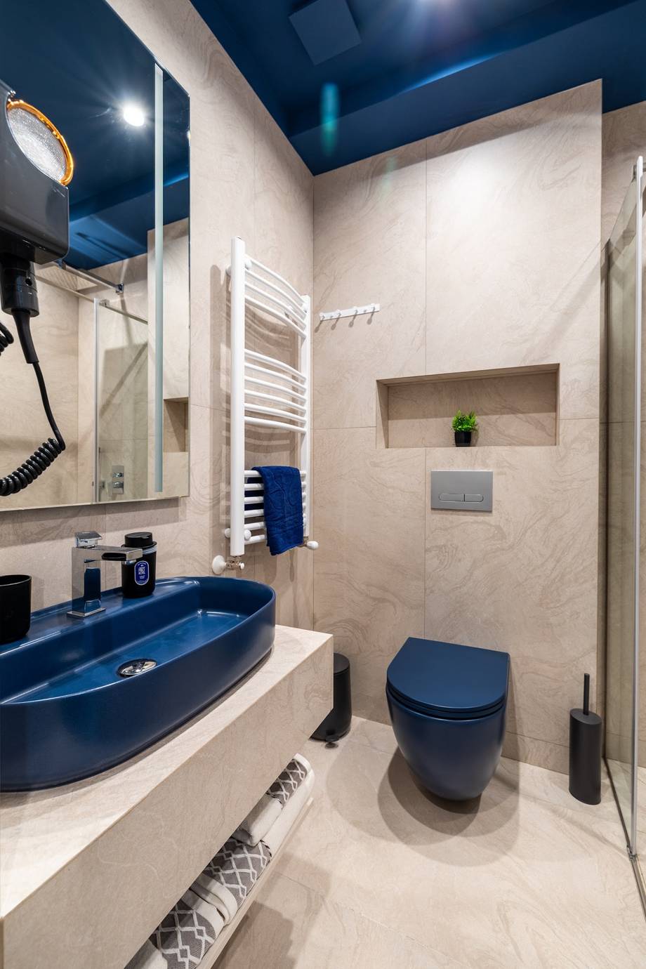 Modern bathroom with blue sink and navy tile accents