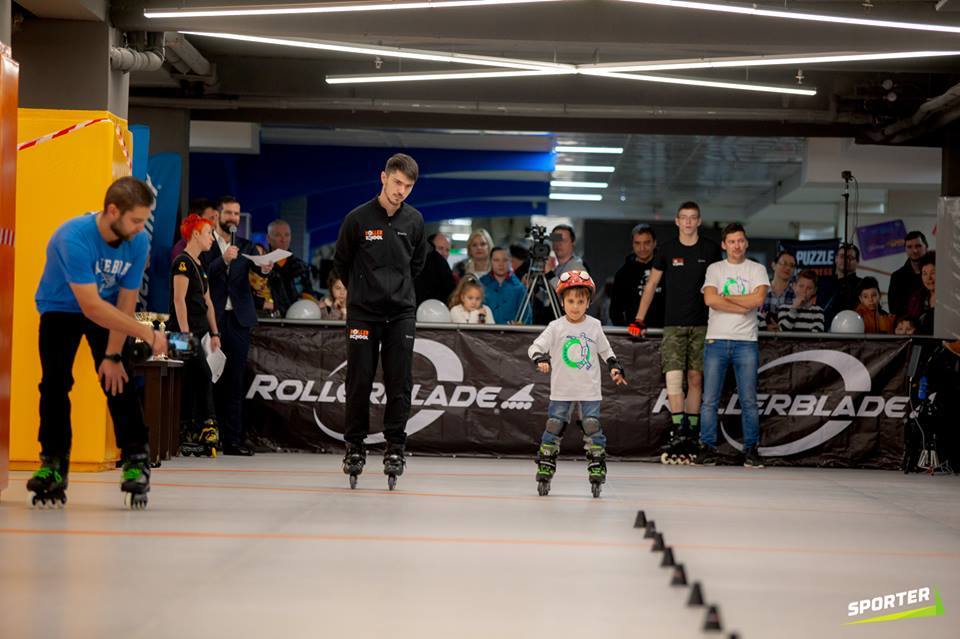 Children learning inline skating in a modern sports facility with instructors and safety barriers