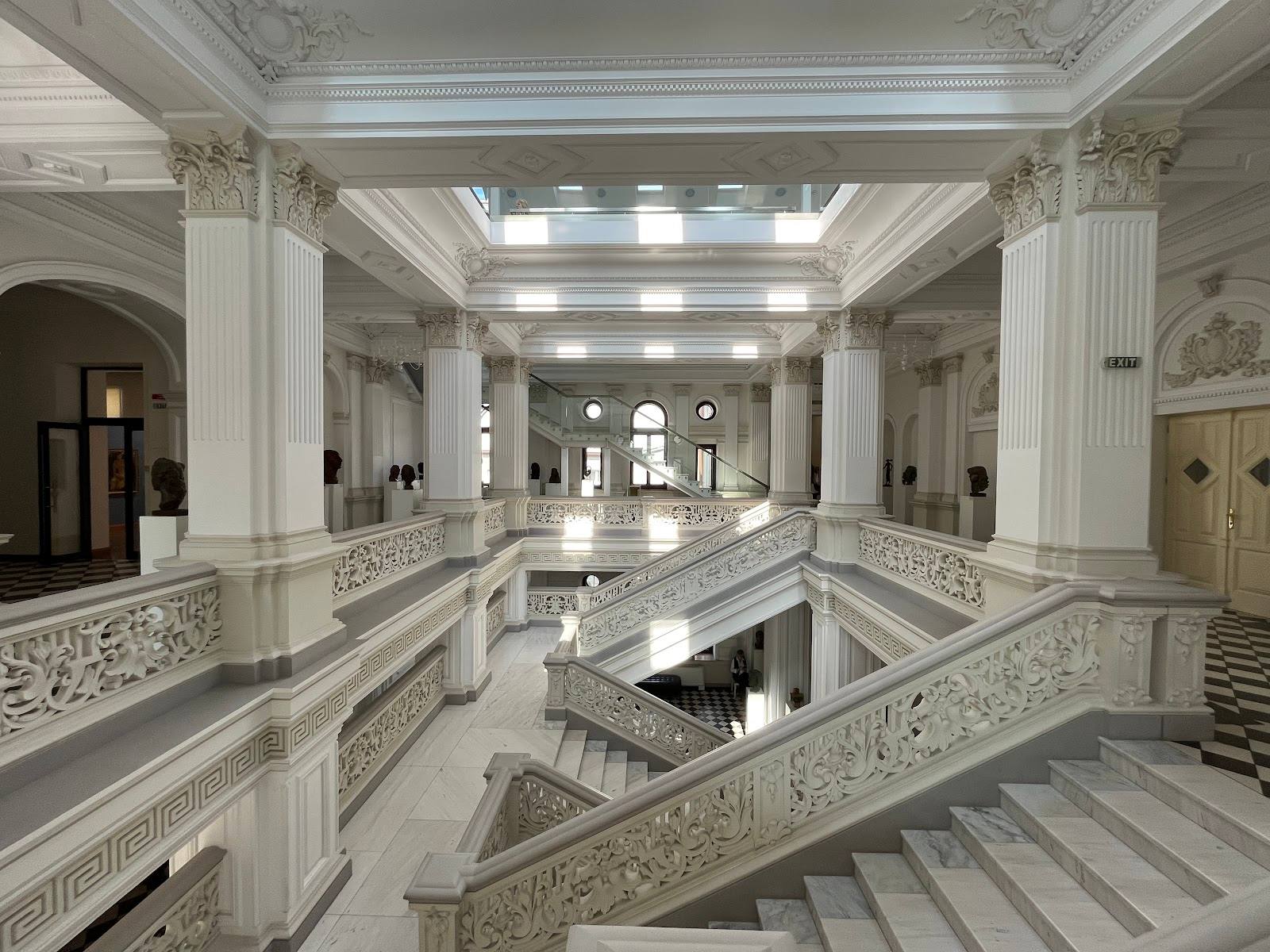 Grand neoclassical staircase hall with ornate balustrades and soaring columns