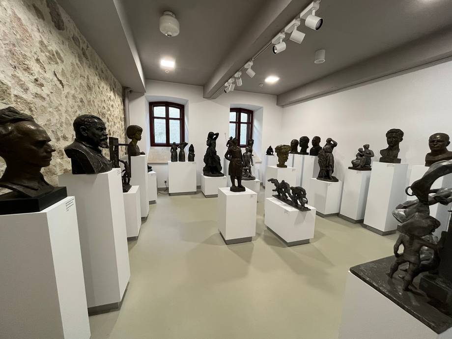 Modern gallery space with black busts on white pedestals and polished concrete floors