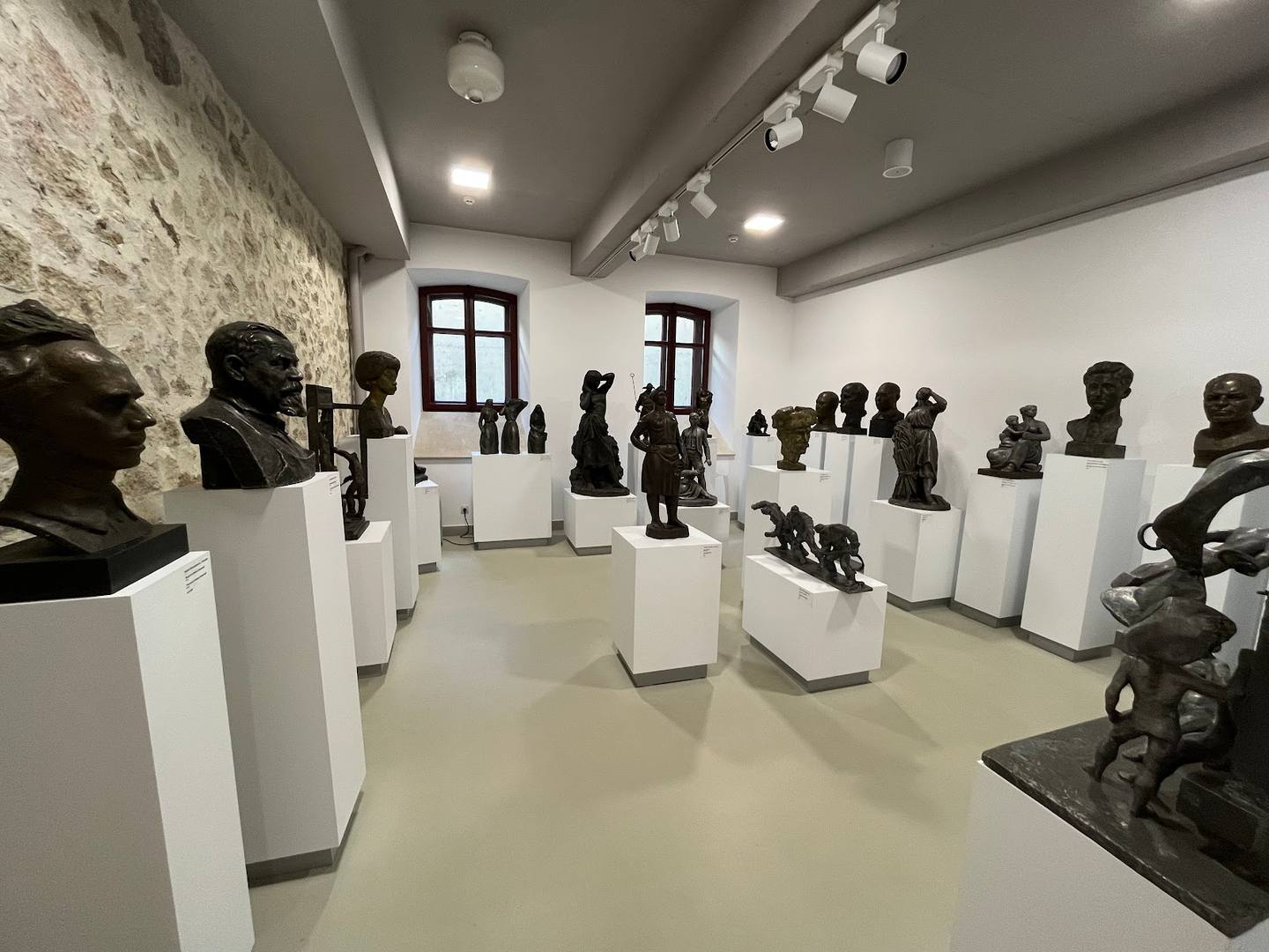 Modern gallery space with black busts on white pedestals and polished concrete floors