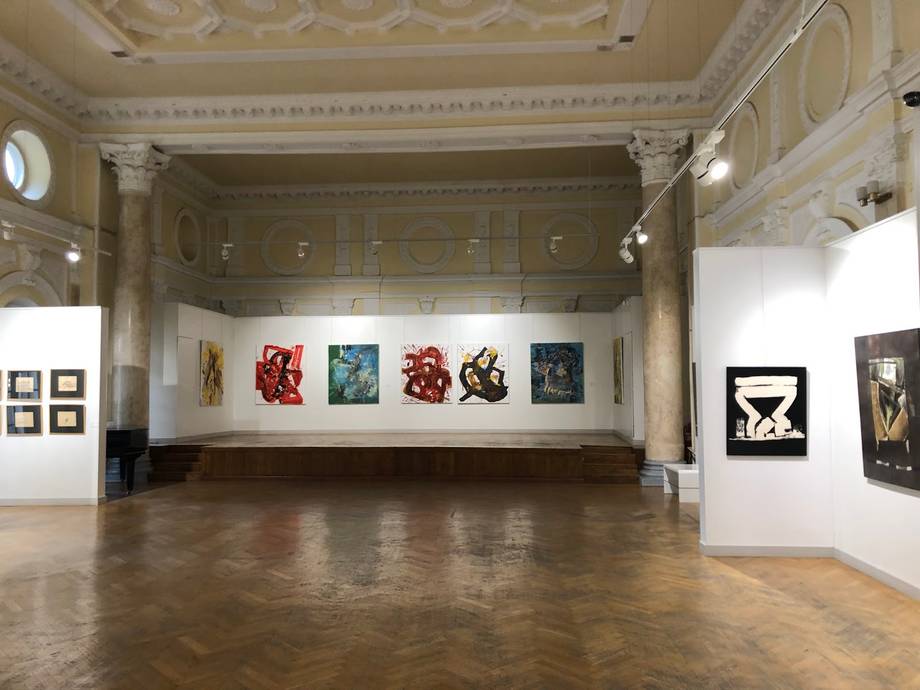 Grand gallery interior with ornate ceiling, polished wood floor, and contemporary artwork displays