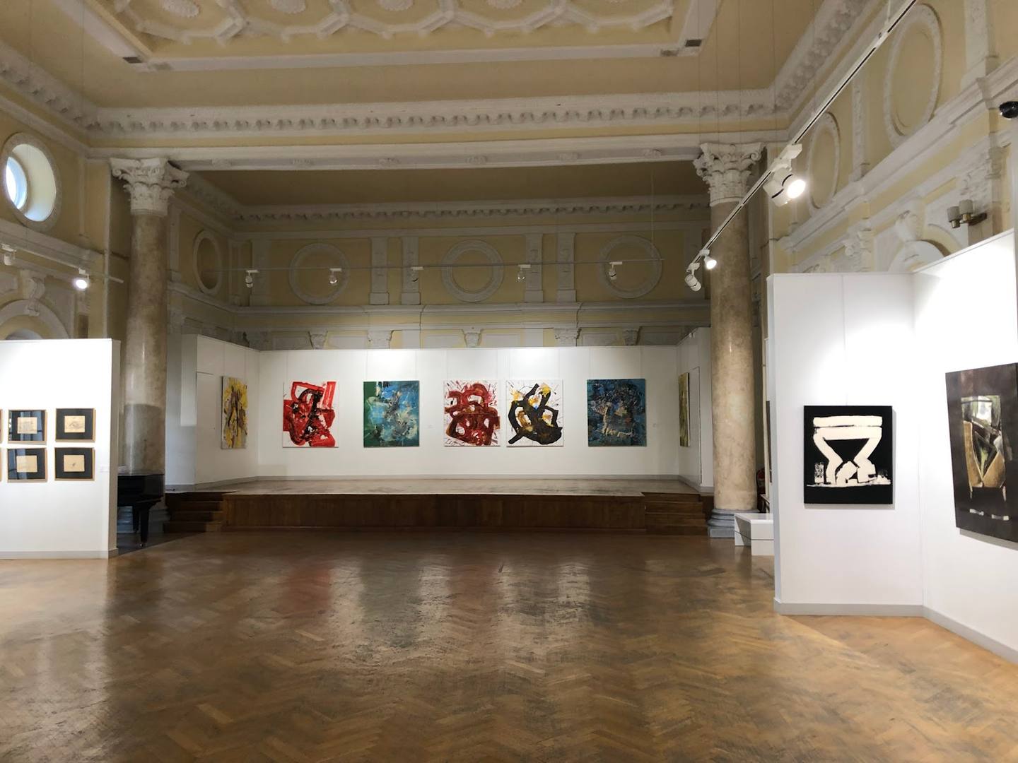 Grand gallery interior with ornate ceiling, polished wood floor, and contemporary artwork displays