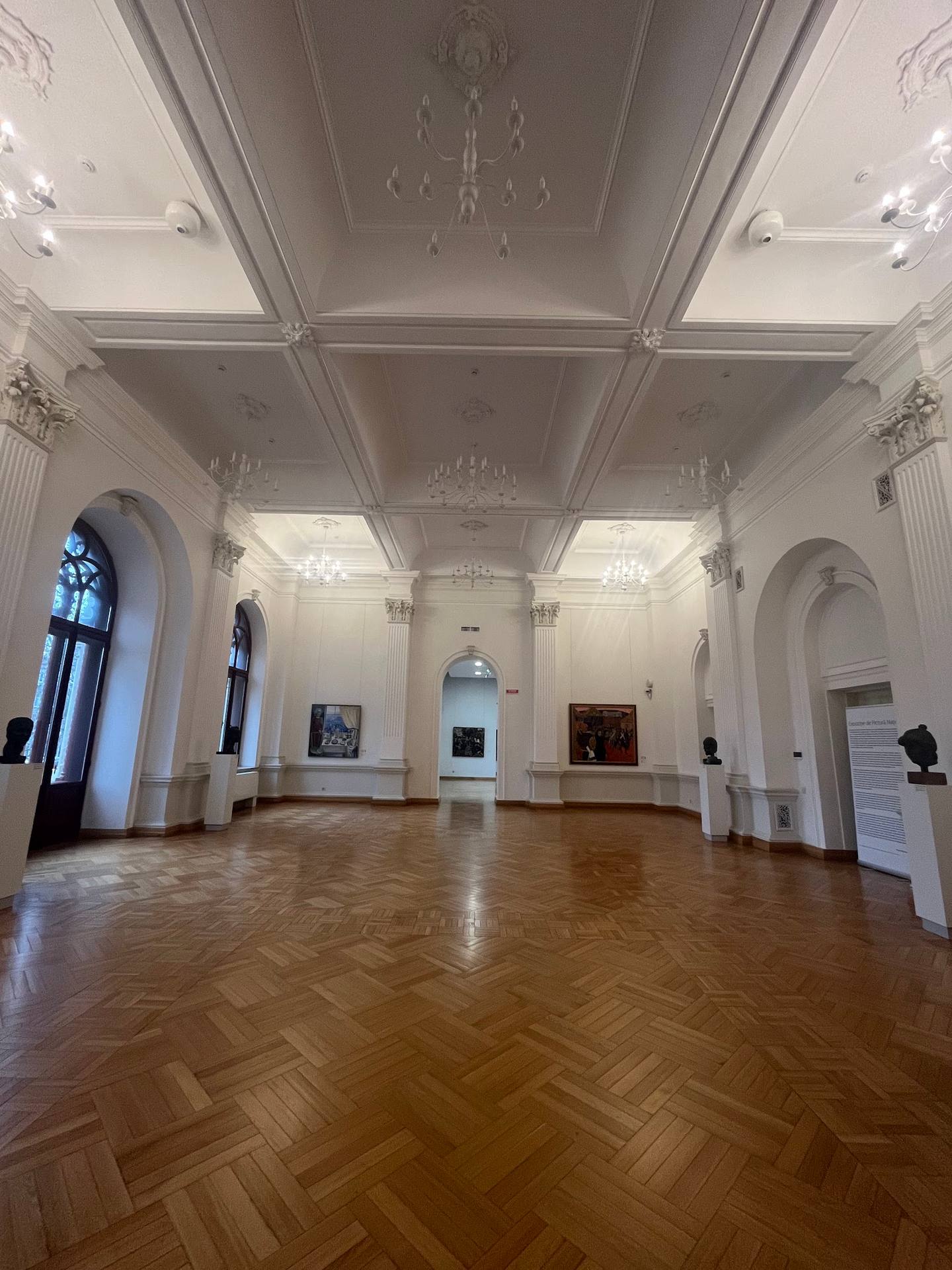 Grand neoclassical exhibition hall with herringbone parquet flooring and symmetrical arches