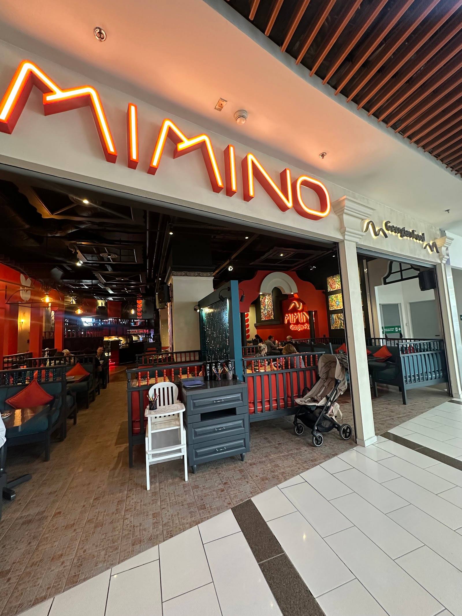 NIMO neon-signed storefront with amber interior lighting and casual seating area