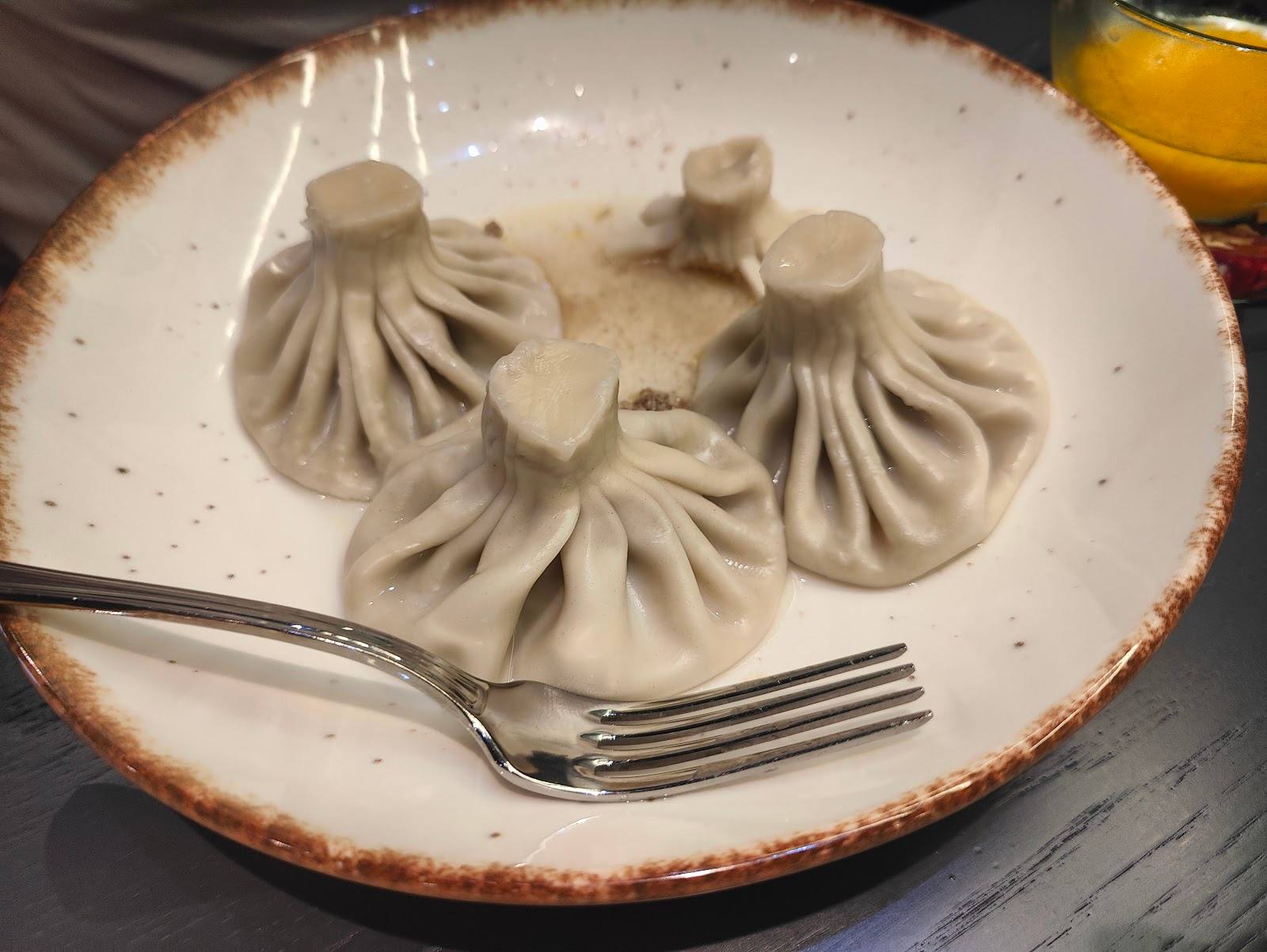Steamed dumplings plated on ceramic dish with fork
