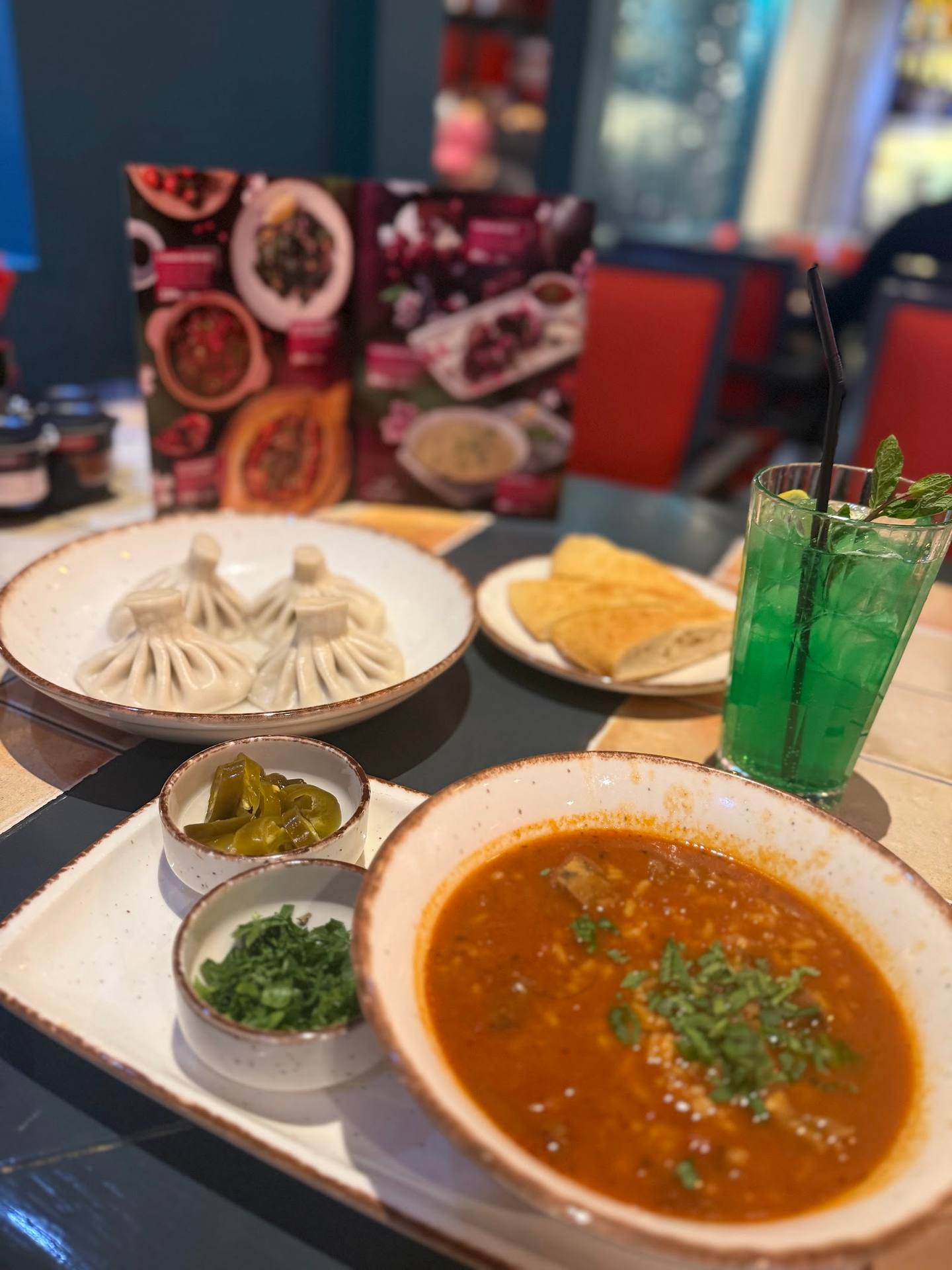 Table setting with soup, dumplings, chips, and green beverages at restaurant