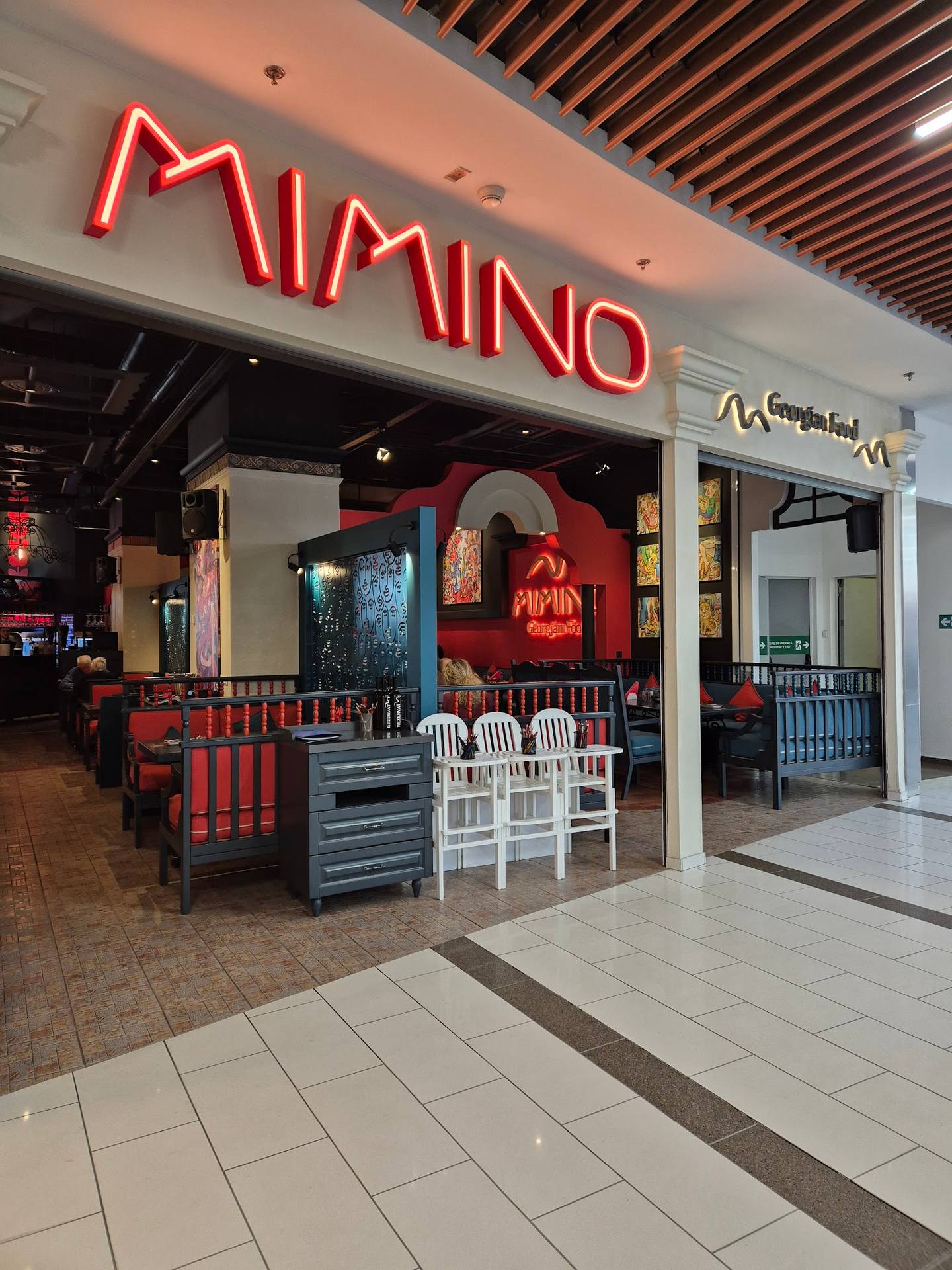 AMINO restaurant storefront with neon signage and wood-accented interior seating visible