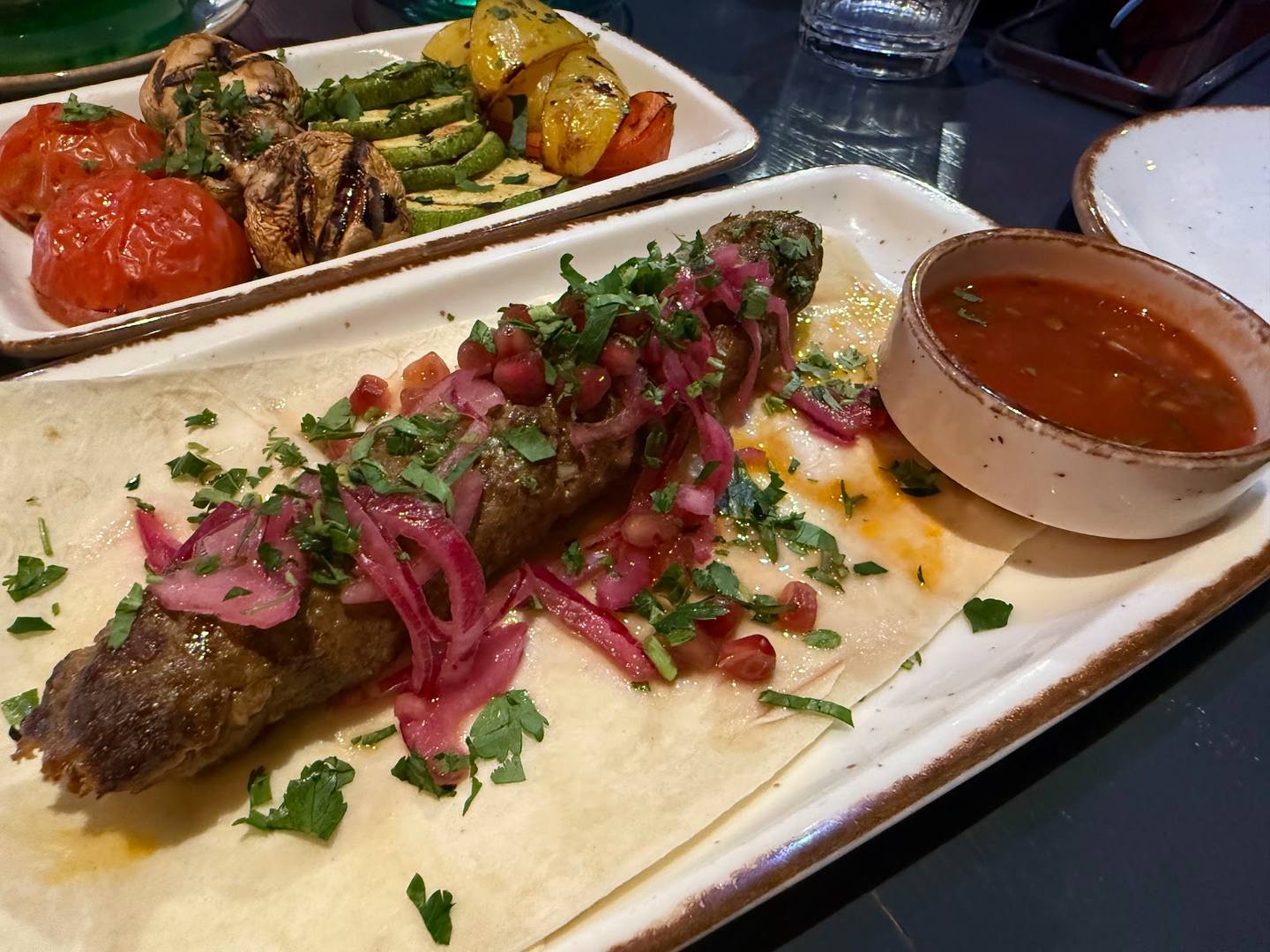 Grilled meat with pickled vegetables and sauce on white plate