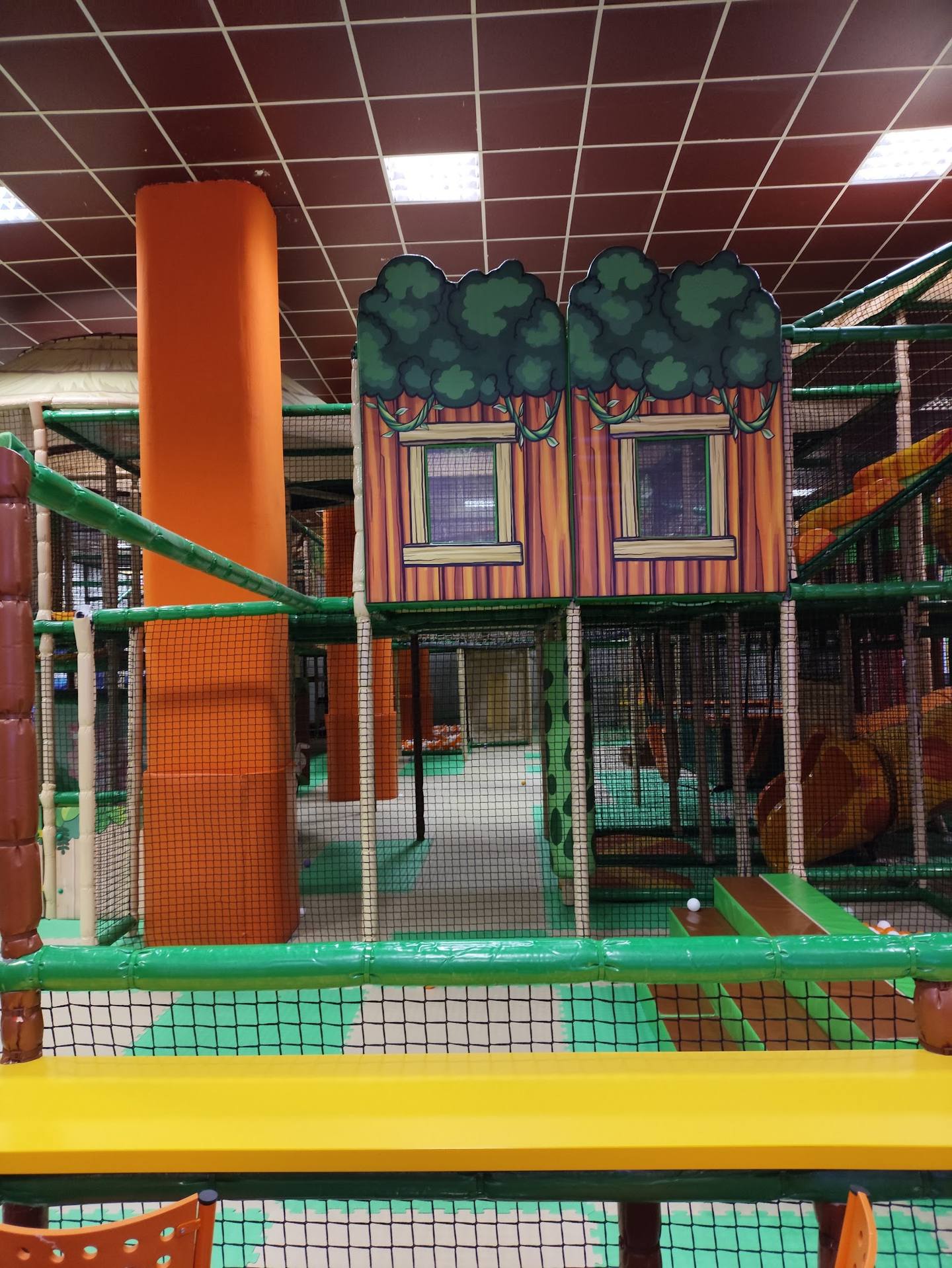 Children's play structure with climbing tower, slides, and interactive activities in indoor play center