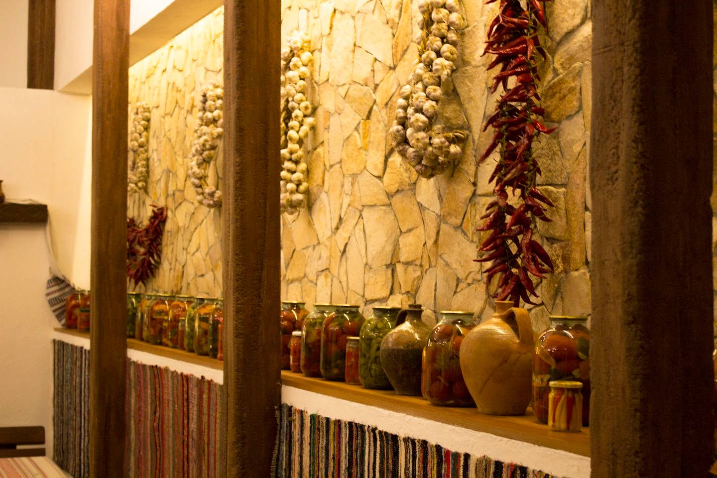 Rustic interior with dried peppers, garlic braids, and ceramic vessels on display shelves