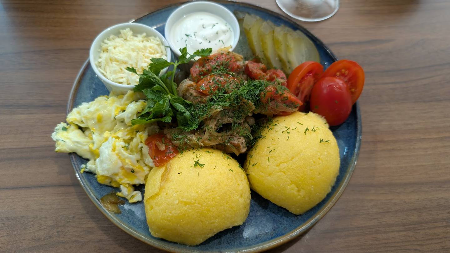 Grilled meat platter with boiled potatoes, vegetables, and sour cream sauce