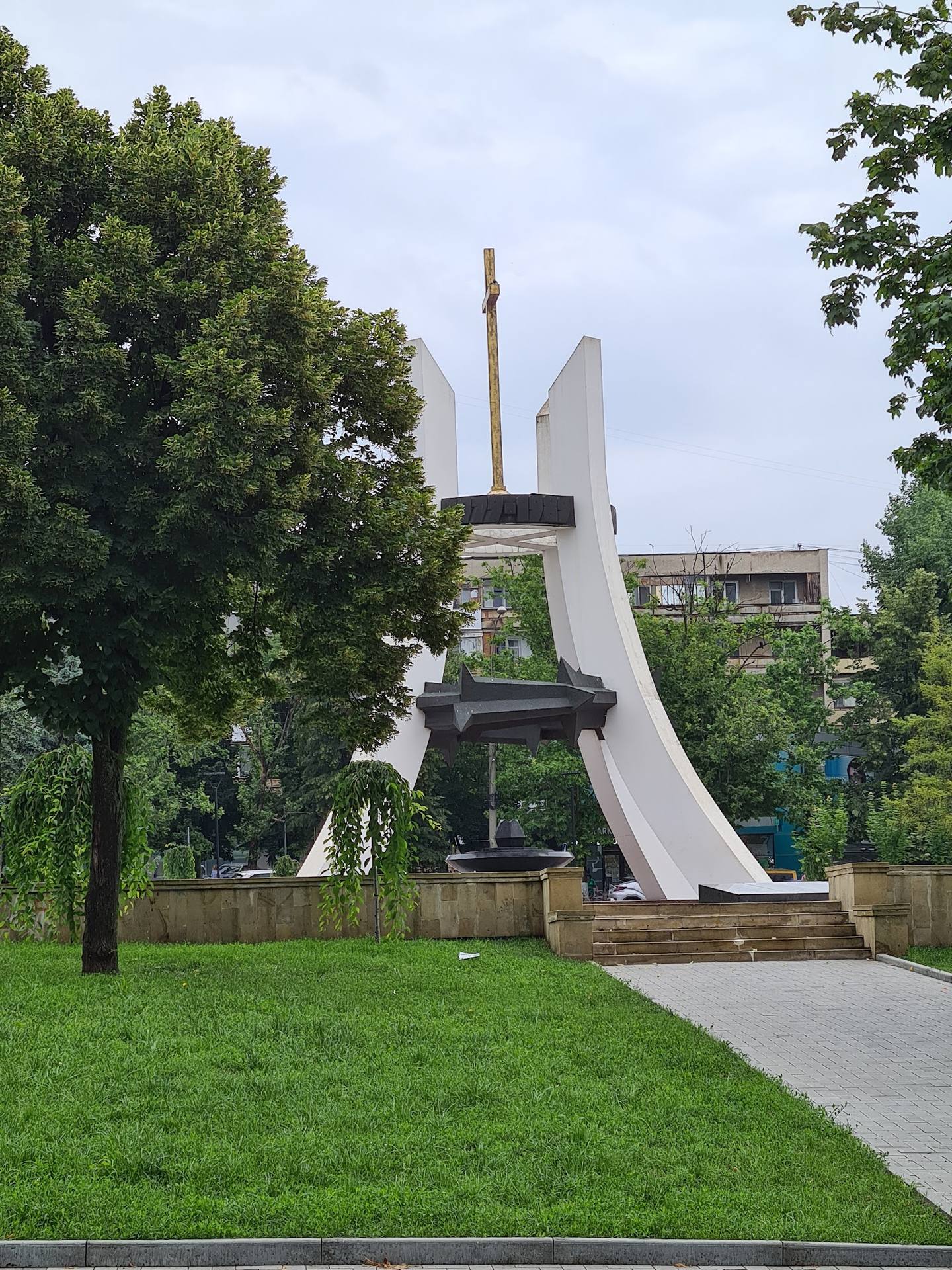 Iconic modernist monument sculpture in public park with manicured lawn and mature trees