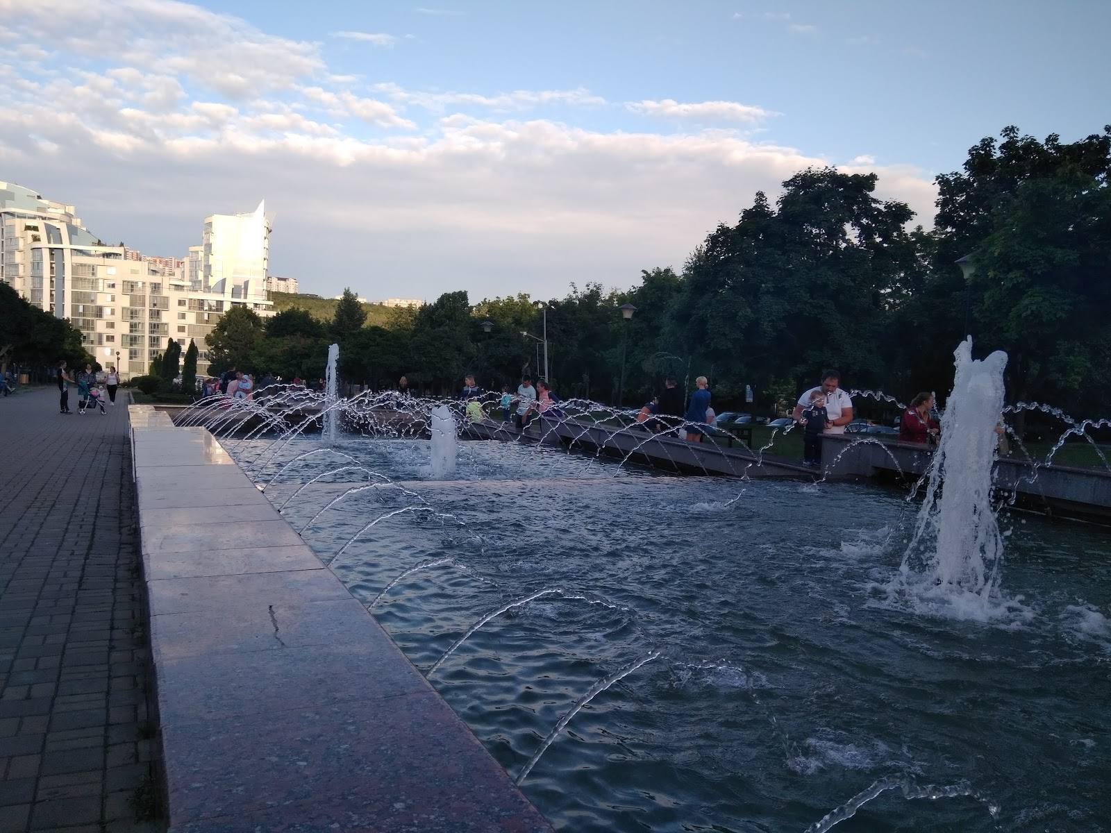 Public plaza with fountain and flower beds overlooking urban skyline