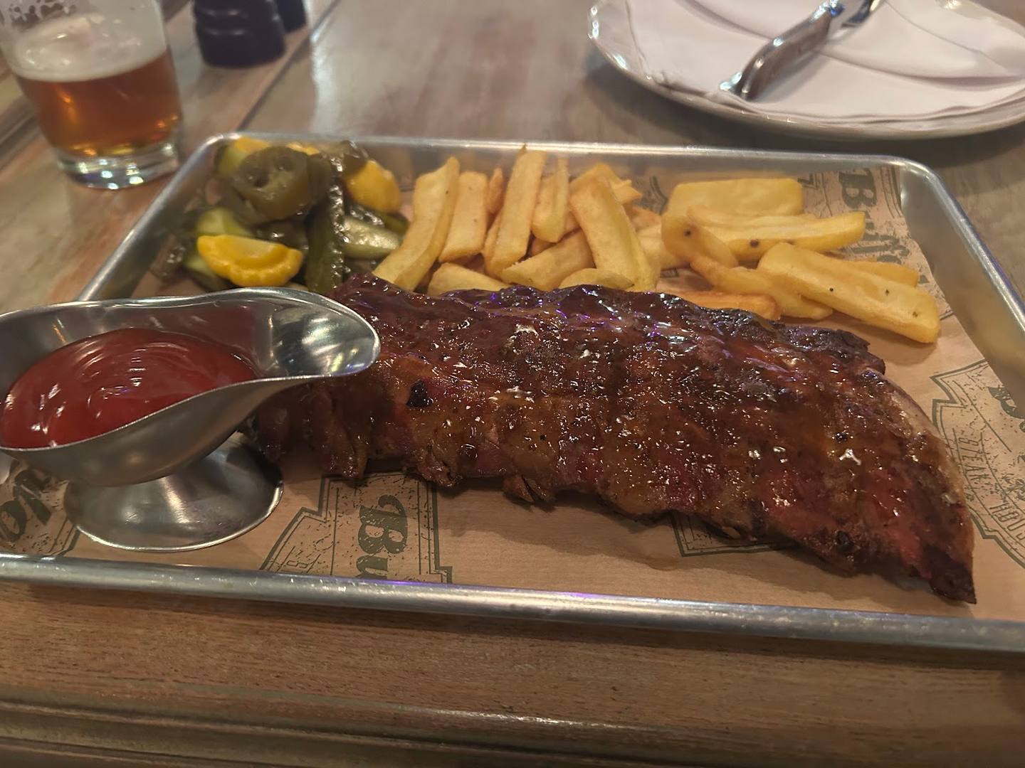 Grilled steak with fries and sauce on wooden serving board