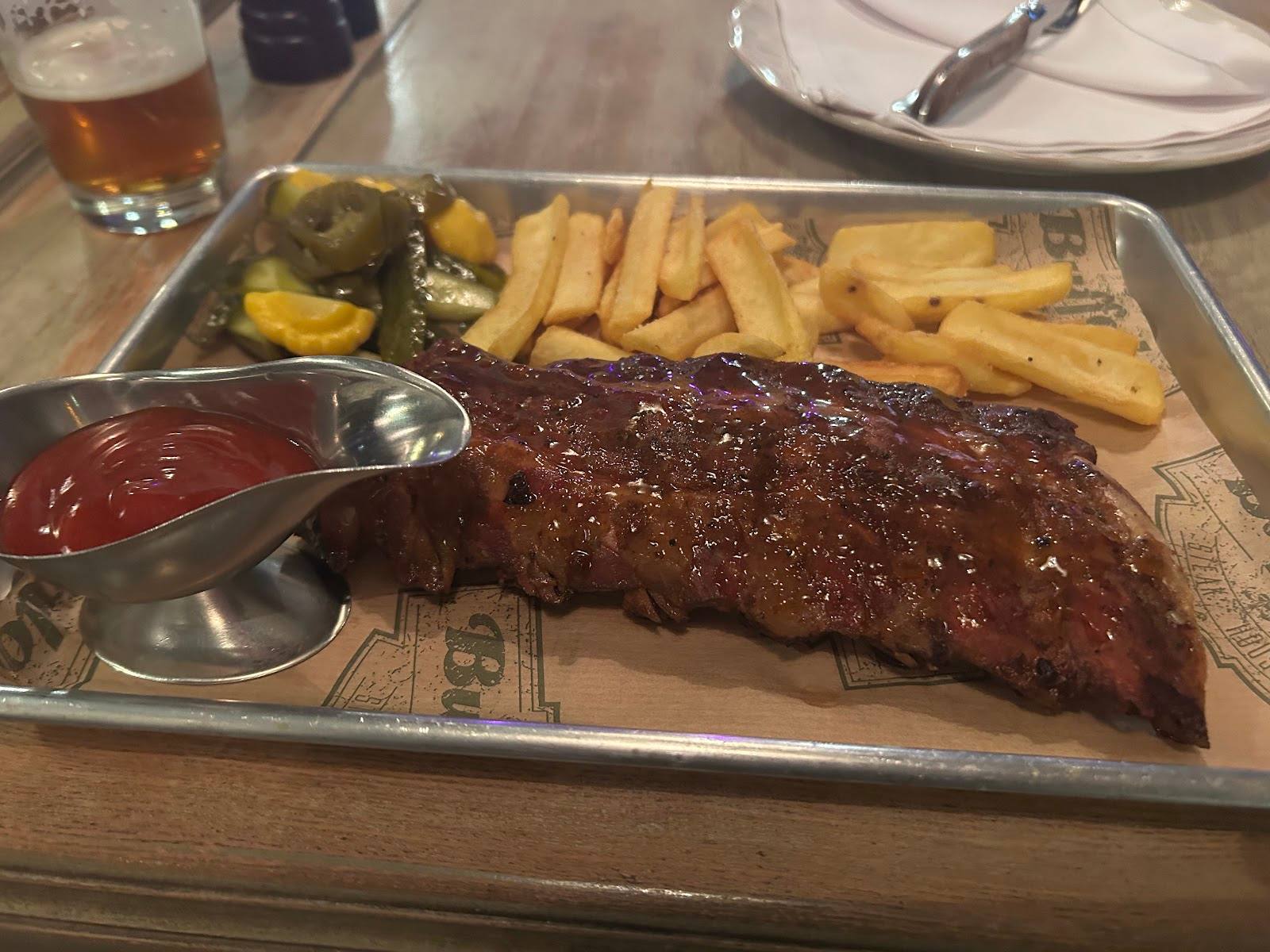 Grilled steak with fries and sauce on wooden serving board