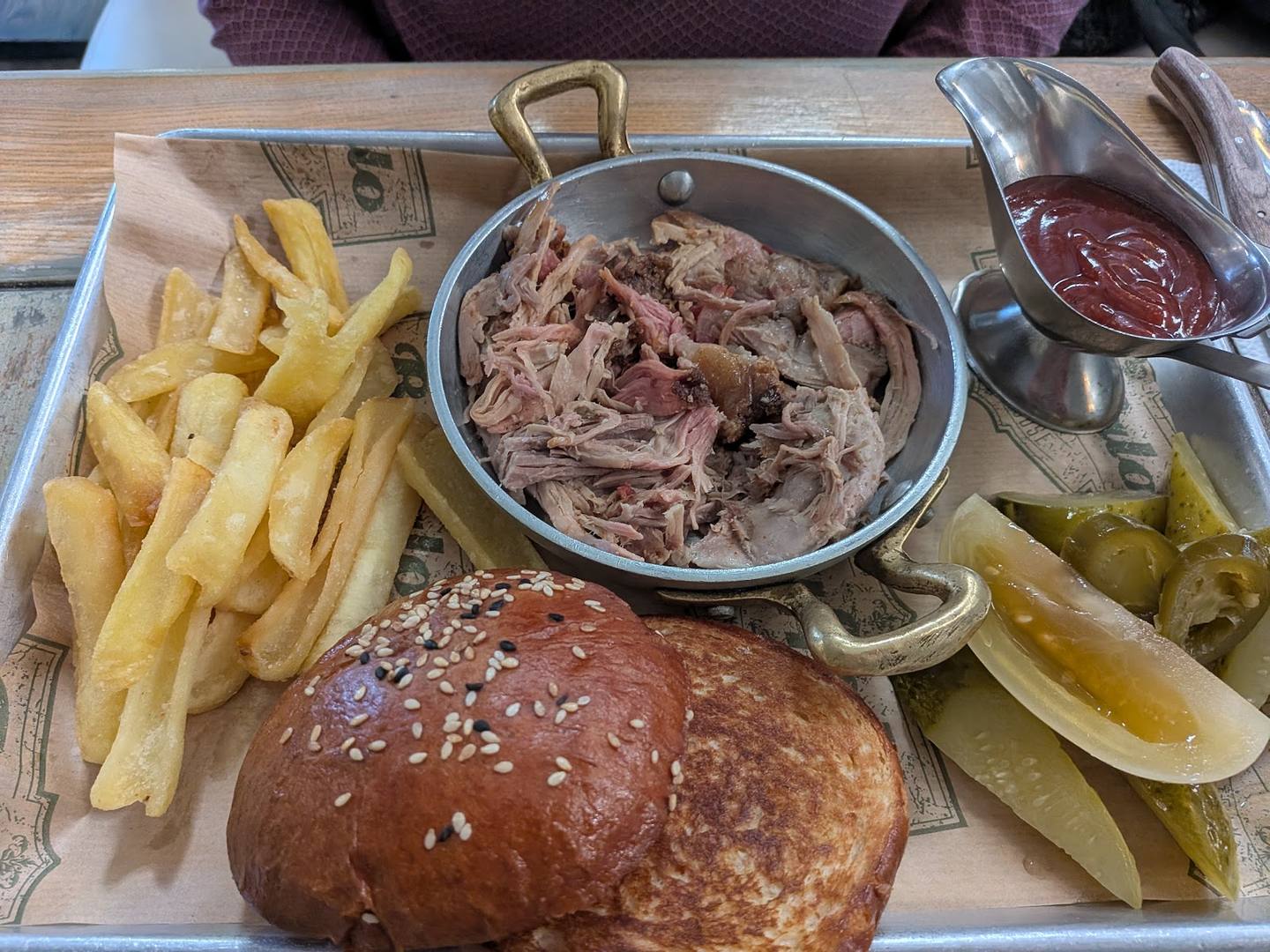 Pulled meat burger platter with fries and pickles on wooden board