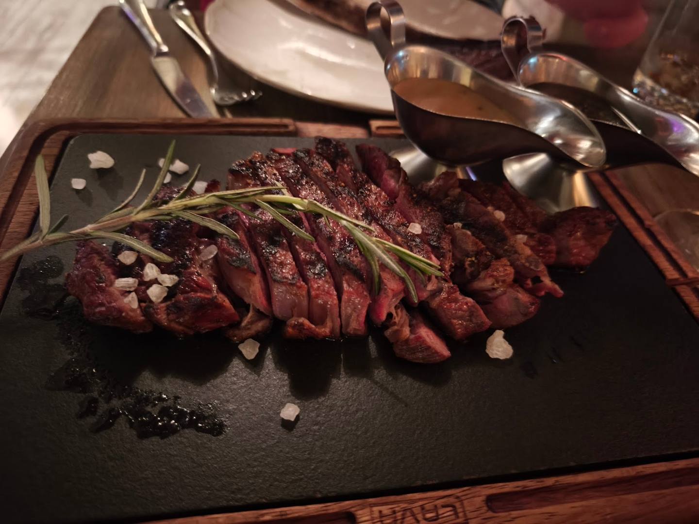 Sliced rare steak with rosemary and sea salt on slate plate