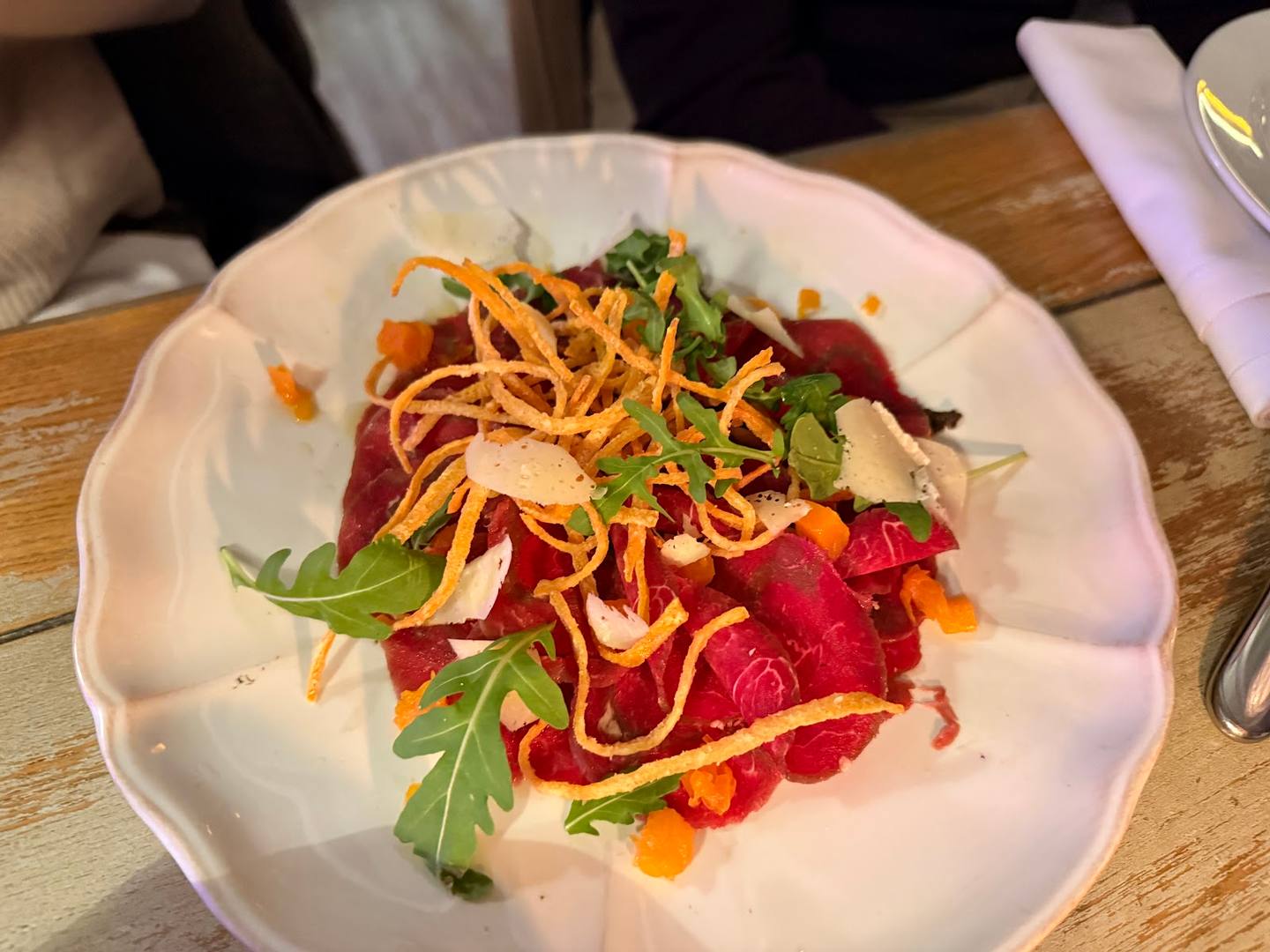 Plated carpaccio with crispy noodles, arugula and microgreens