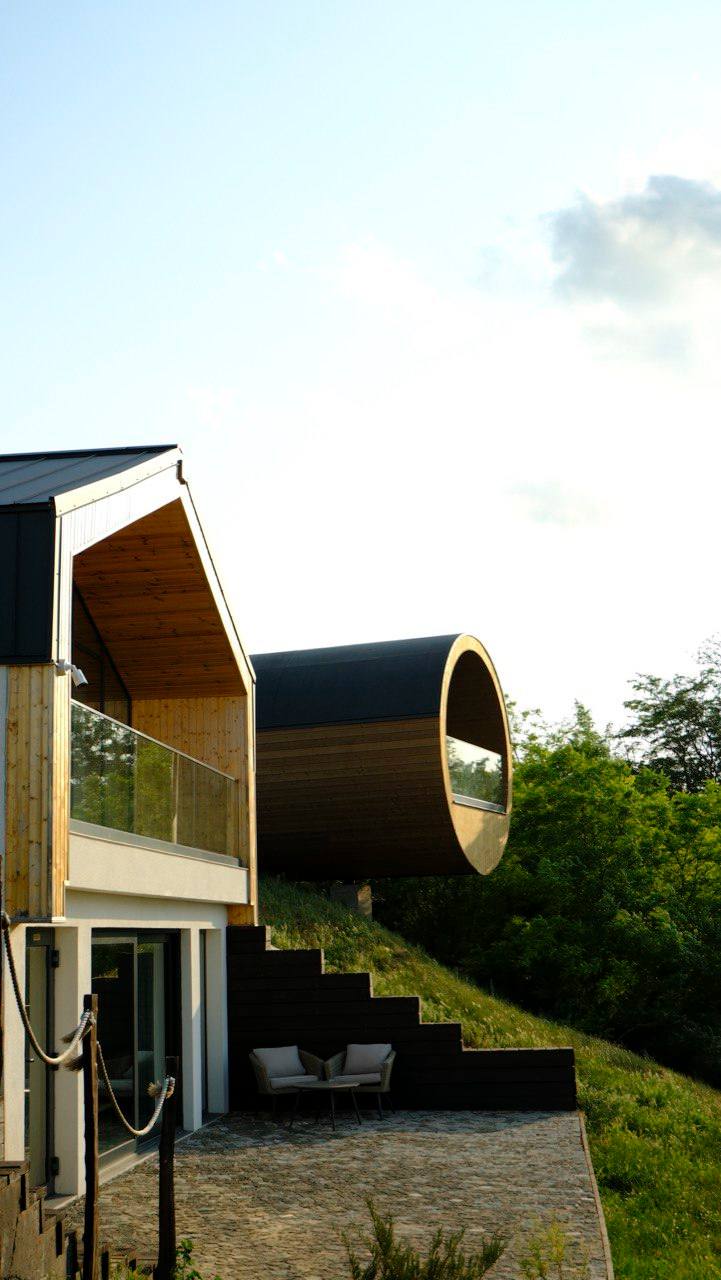 Modern architectural venue with dramatic cylindrical tunnel structure and hillside setting
