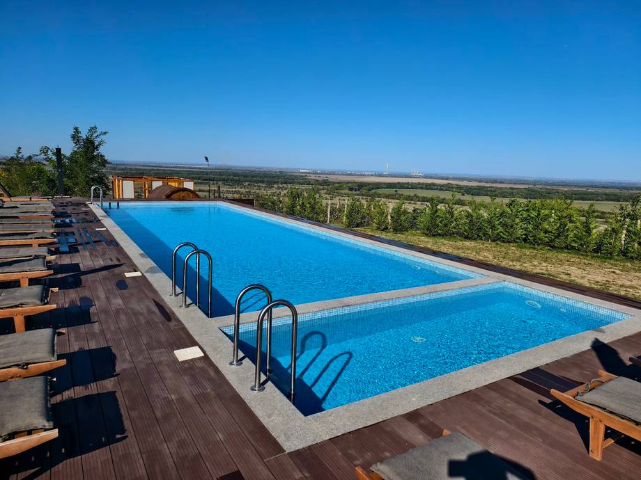 Olympic-size swimming pools with lounge seating overlooking vineyards at dusk
