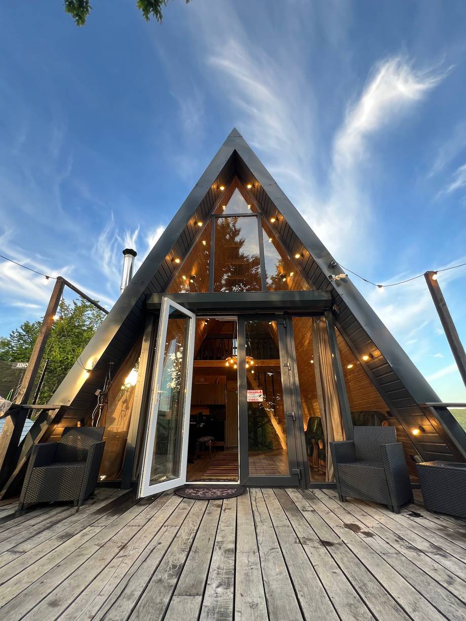 Modern A-frame glass pavilion with dramatic pitched roof and warm interior lighting