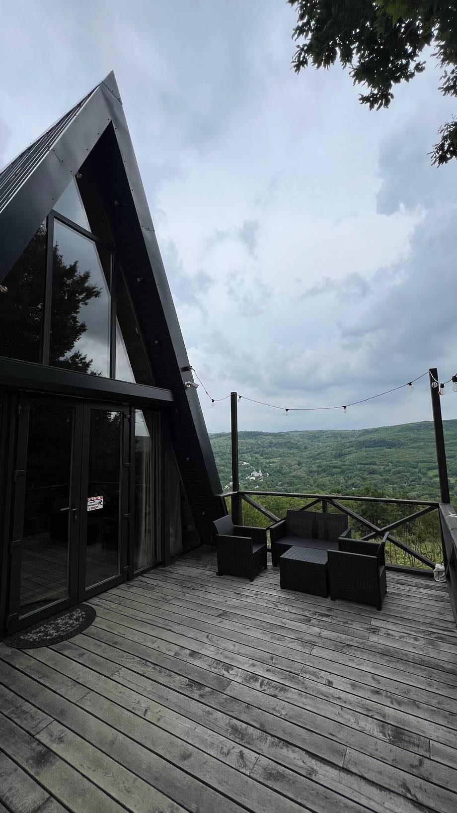 Modern A-frame structure with terrace overlooking rolling hills landscape