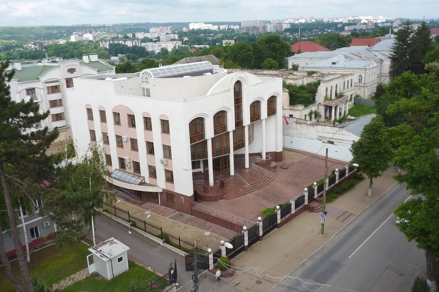 Aerial view of distinctive white modernist building with arched facade and red-brick plaza