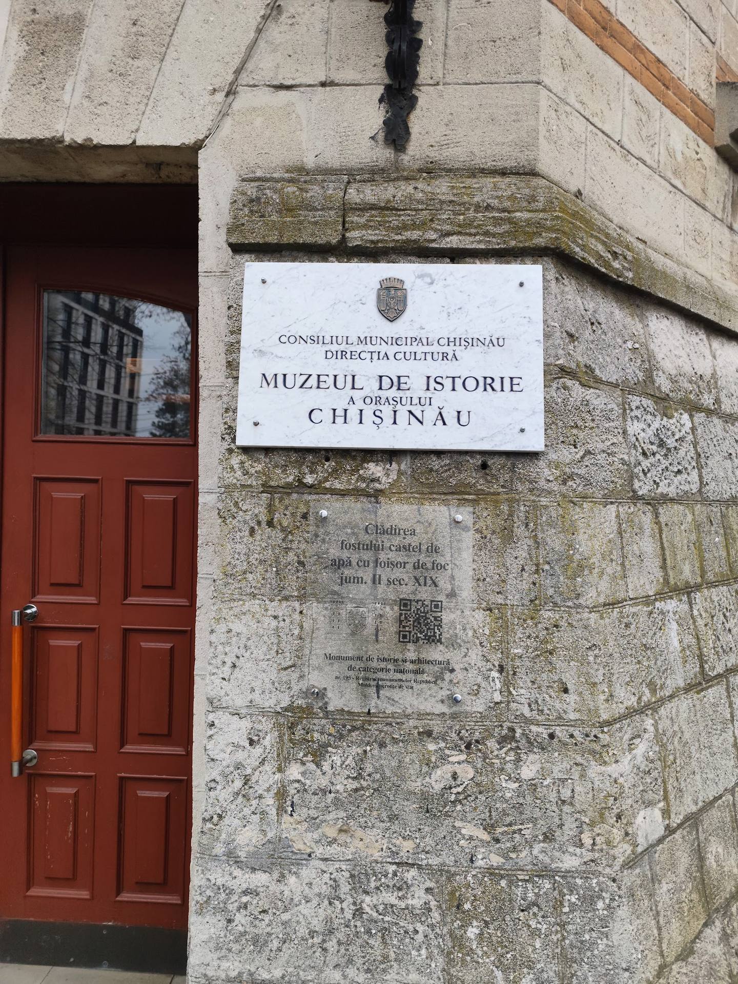 Historic stone building facade with Museum of History plaque and red wooden door, Chișinău