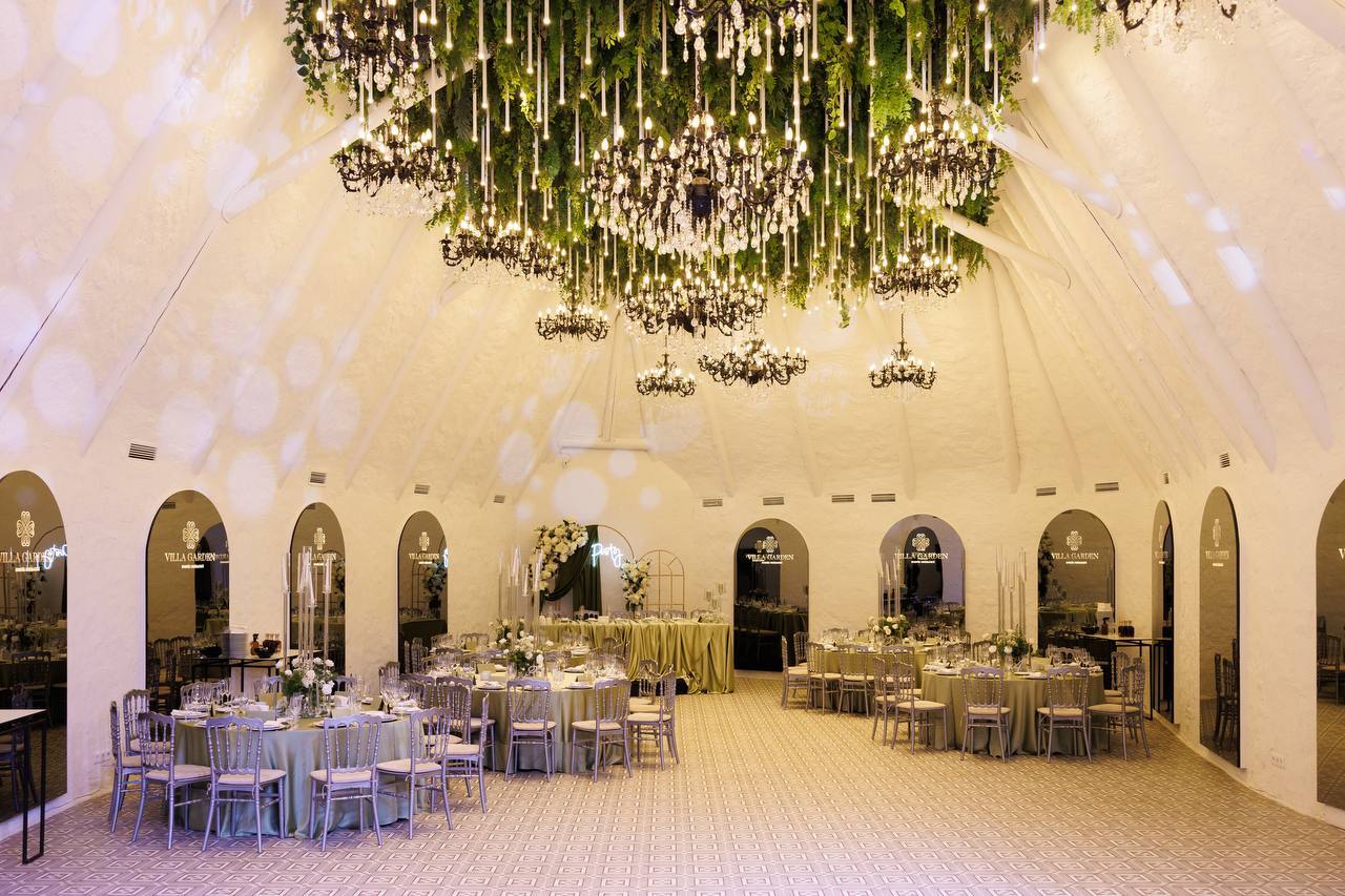 Elegant reception hall with arched ceilings, hanging greenery, and lavender-lit ambiance