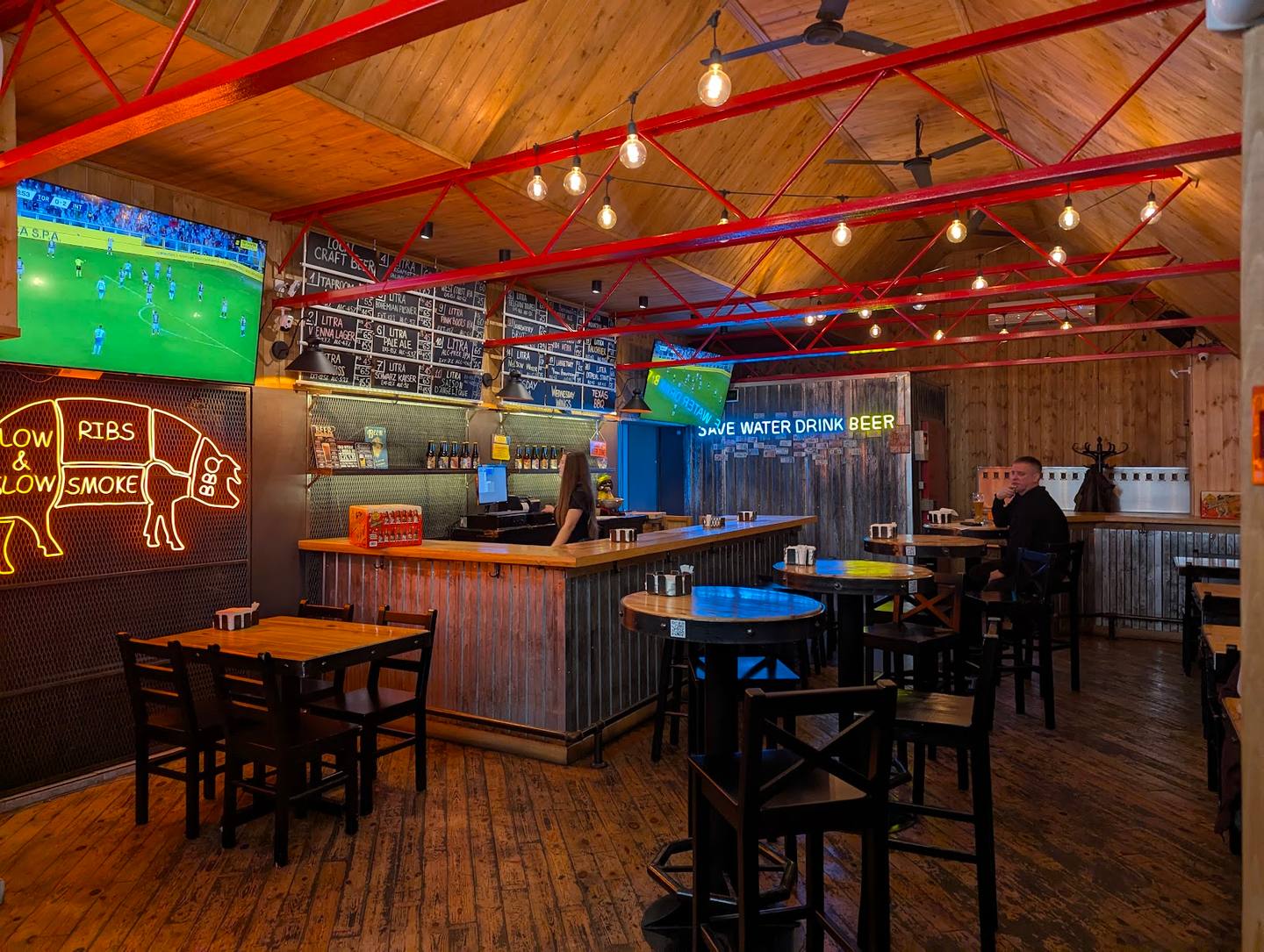 Casual sports bar interior with wooden beams, neon signage, bar counter and dining tables