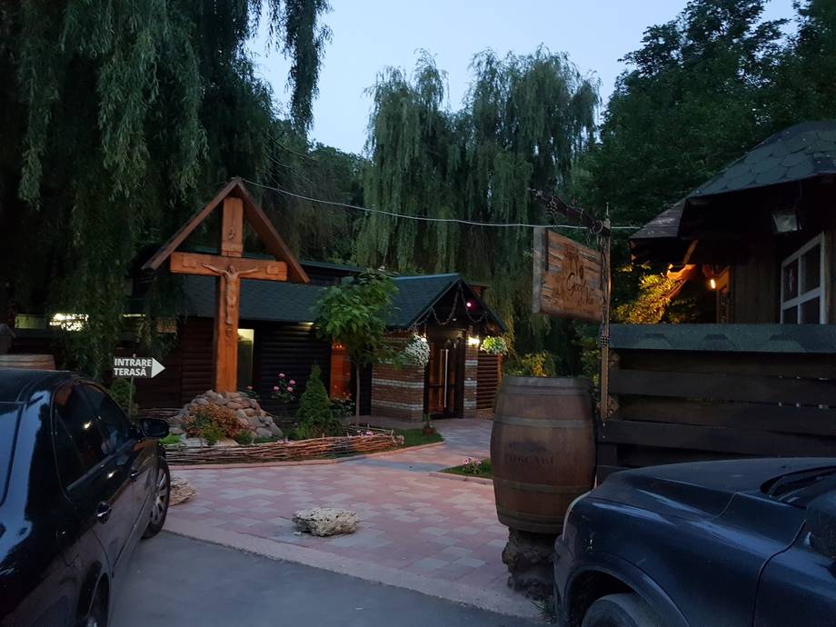 Rustic winery entrance with wooden cross and willow trees at dusk
