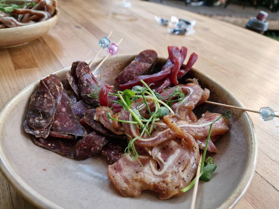 Charcuterie platter with cured meats, microgreens, and garnishes on white plate