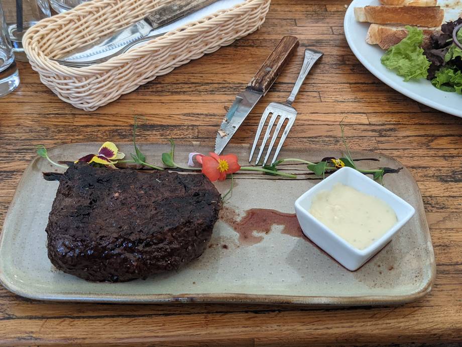 Grilled steak with herb garnish and butter sauce on wooden table