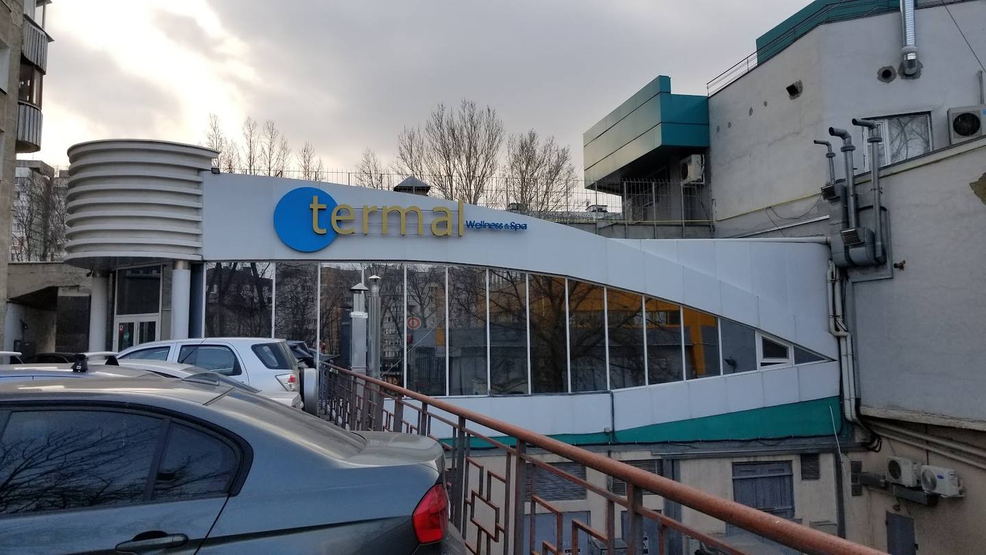 Modern white building with blue signage and large storefront windows, industrial area setting
