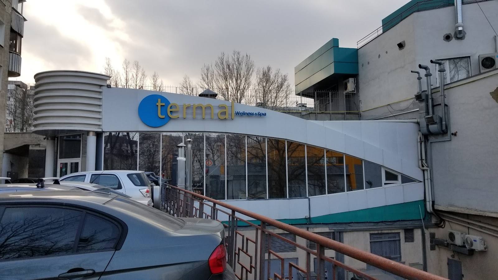 Modern white building with blue signage and large storefront windows, industrial area setting
