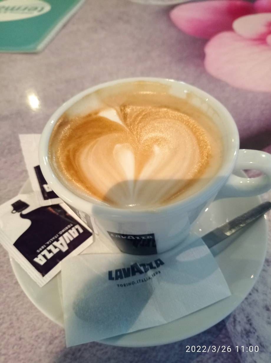 Latte with latte art served on Lavazza-branded saucer