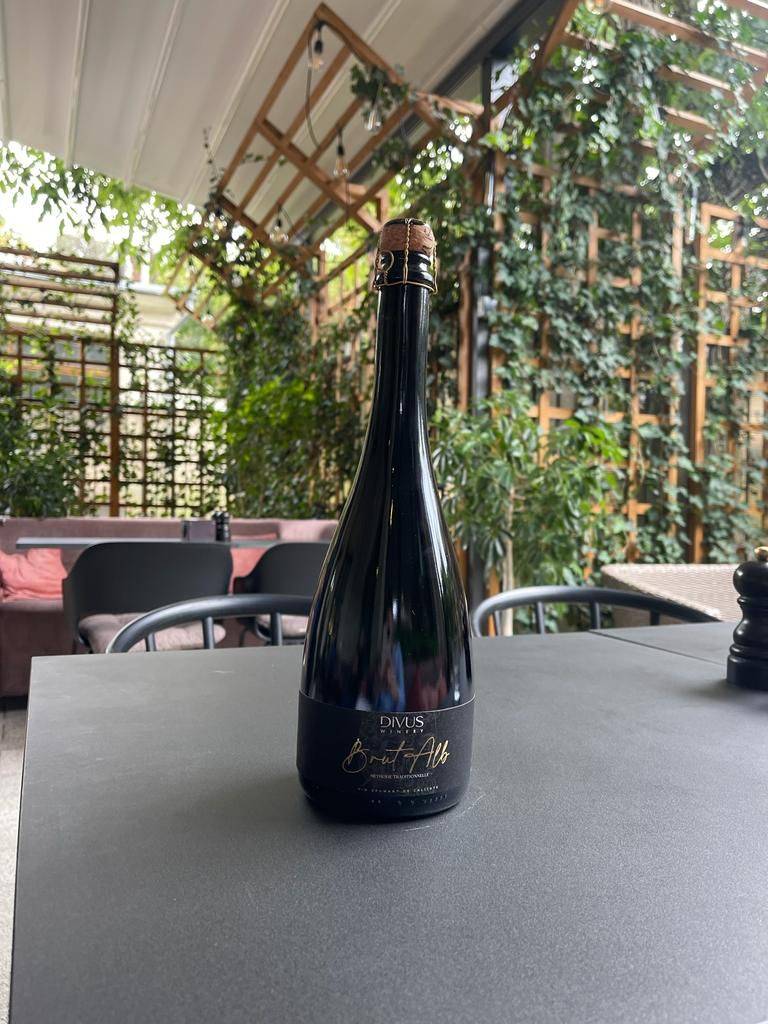 Wine bottle displayed on table in modern wine bar with living green walls and polished concrete surfaces.