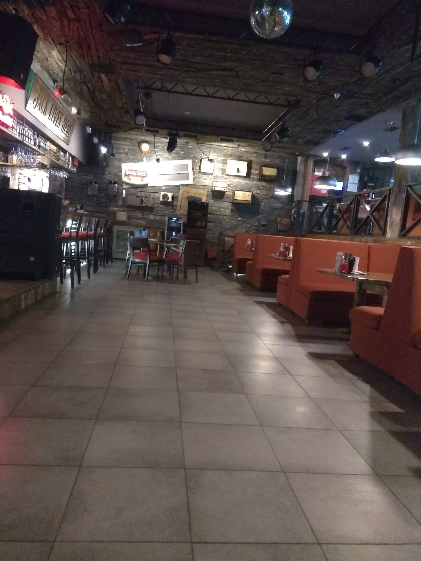 Interior dining space with orange seating and industrial-style ceiling with signage